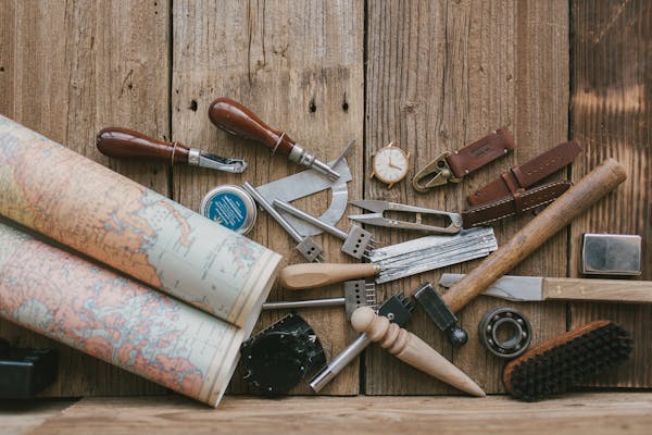 Collection of leather crafting tools on wooden surface